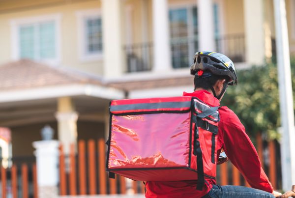 Homem com uma mochila vermelha e equipamentos de segurança para efetuar uma entrega no modelo crowdshipping.