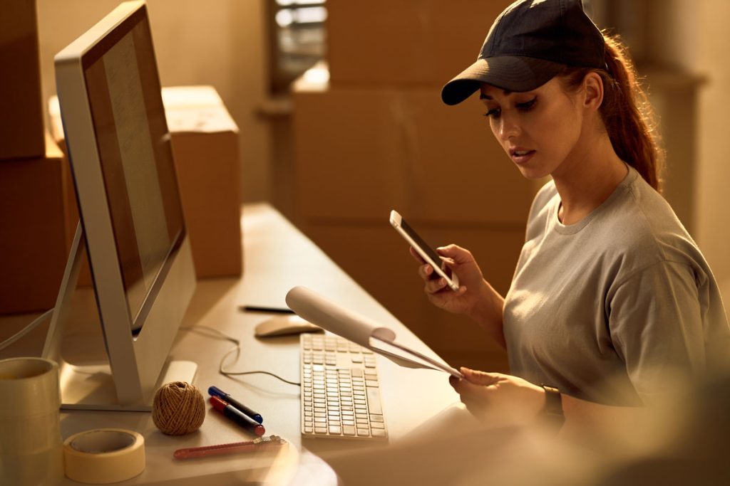 Mulher na frente do computador e com prancheta para planejar o processamento de pedidos e as etapas na dark store